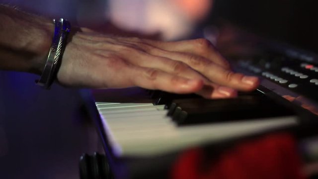 hands of a man playing an electronic piano