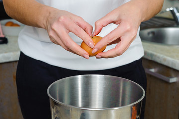 A woman is cooking in her kitchen, about to bake a cake. woman breaks eggs, separates proteins from yolks, close-up