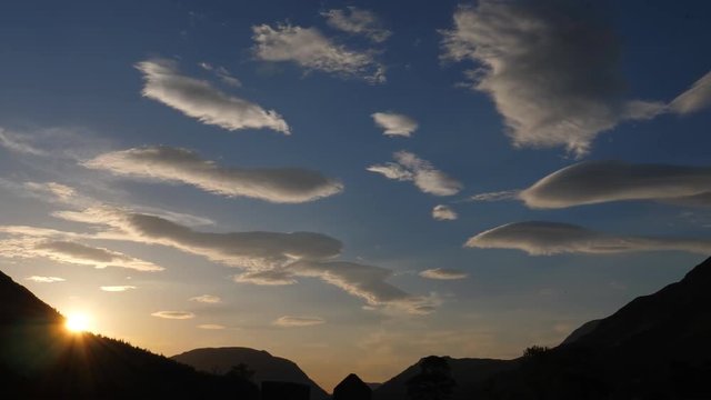 Slow panning shot showing lenticular clouds on sunset sky in the mountains