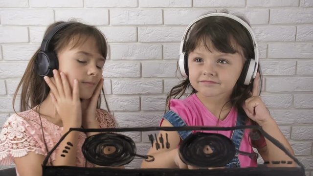 The child listens to music. Cheerful little girls in headphones plays the DJ.
