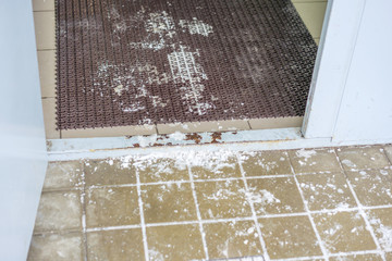 slippery surface near the entrance to the house entrance, winter time, foot cleaning mat