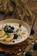 Bowl of oatmeal with fresh blueberries banana topping, selective focus