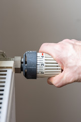 Male hand changing temperature on radiator.