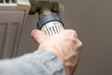 Male hand changing temperature on radiator. Heating season. Heating season. Savings in the bill. Saving Energy Concept.