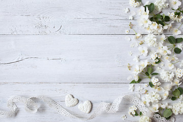 White wooden background with white spring flowers, hearts and lace ribbon - obrazy, fototapety, plakaty