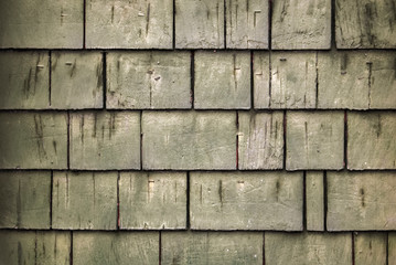 Rustic rough wood shingle background with greenish hue and spots of white paint