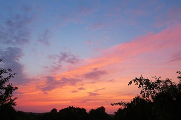 Beautiful pink sunset on blue sky and trees background