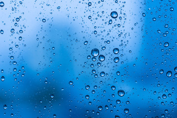 Naklejka na ściany i meble Water drops on glass window blue background after the rain in the autumn fall