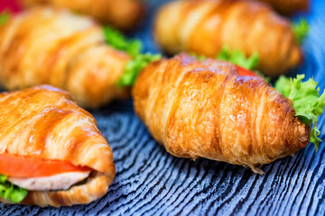 Close up fresh croissants with salad, ham and cheese on table
