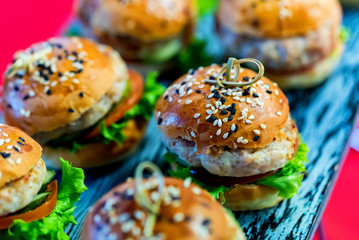 Tasty homemade mini-hamburgers on wooden board close