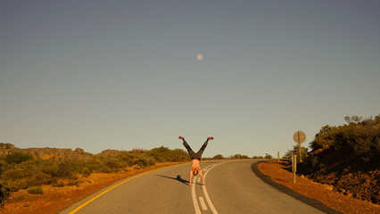 Man doing a handstand on the road in Rocklands near Cape Town, South Africa.