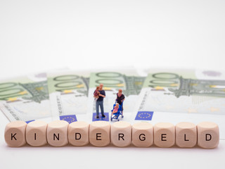 Eltern mit Kindern auf Geldscheinen mit Schrift Kindergeld
