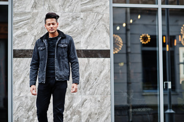 Handsome and fashionable indian man in black jeans jacket posed outdoor.