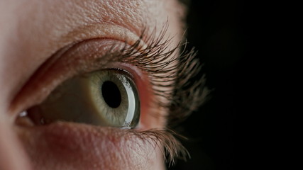 close up macro green eye blinking looking curious light reflecting on iris