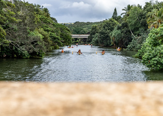 Hawaiian natives paddling on the Haleiwa River in a Outrigger canoe (Hawaiian canoe) passing under the Haleiwa Bridge on the island of Oahu in Hawaii on a cloudy day
