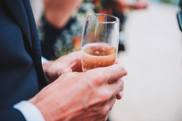 Close up of man holding a glass of cold champagne or sparkling wine at a party