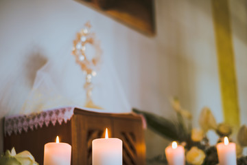 Detail of burning candles in the curch and holy eucharist in the background