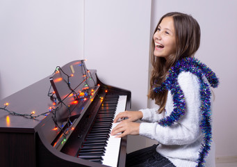 Young girl child plays piano. There are lights on the piano..