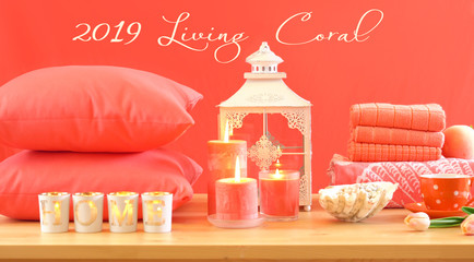Living Coral 2019 Color of the Year homewares table setting with candles, towels, and throw...