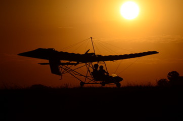 Naklejka na ściany i meble Ultralight airplane at sunset. Ultralight ride. Tranquility in flight with ultralight aircraft