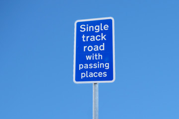 Single track road with passing places sign post against blue sky