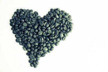 Beautiful texture in the shape of a heart from freshly roasted selected delicious saturated brown natural fragrant Arabica and Robusta coffee beans. Copy space, flat lay, isolated white background