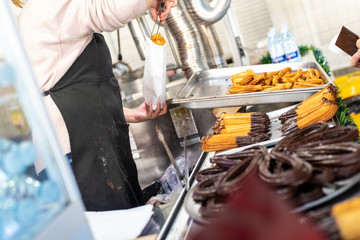 Street vendor stand Fried dough, traditional Spanish breakfast churros bathed in chocolate.