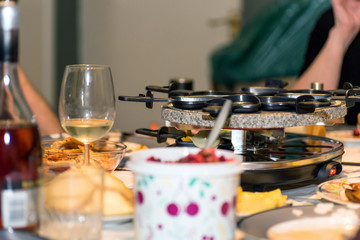 traditional swiss electric raclette stone grill unit with individual skillets on christmas table