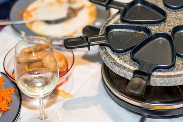 traditional swiss electric raclette stone grill unit with individual skillets on christmas table