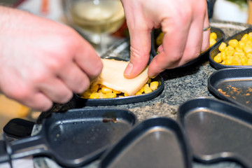 juicy yellow sweet corn on individual skillets getting ready for traditional swiss electric raclette stone grill on christmas table