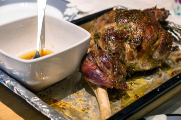 A roast leg of lamb on baking tray on christmas table