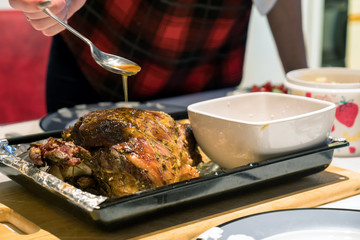 A roast leg of lamb on baking tray on christmas table