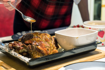 A roast leg of lamb on baking tray on christmas table