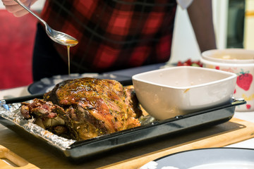 A roast leg of lamb on baking tray on christmas table