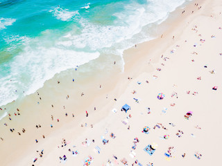 An aerial view of people on the beach with blue water on hot summer's day