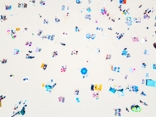 An aerial view of people on the beach with blue water on hot summer's day