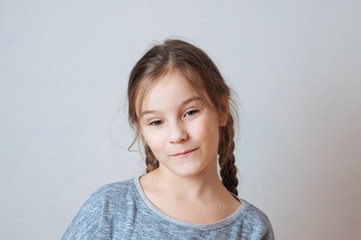 Little girl with a sly look and pigtails on a neutral background
