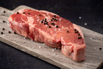 Raw New York Strip Steak on a Dark Slate Surface