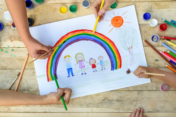 Happy family concept. Co-creation. Children hands draw on a sheet of paper: father, mother, boy and...