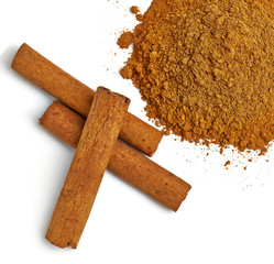 Cinnamon sticks or rolls with powder pile isolated on white background - top view