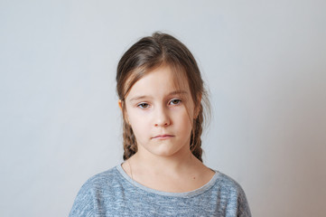 Sad little girl with pigtails portrait on a neutral background