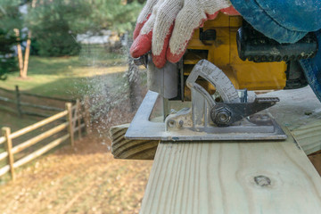 handyman works with circular saw on wooden toprail