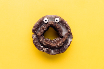 Funny shock face glazed chocolate cake donut on a pastel yellow background, creative minimal...