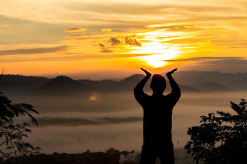 Silhouette of man hand holding sun at winter morning sunrise