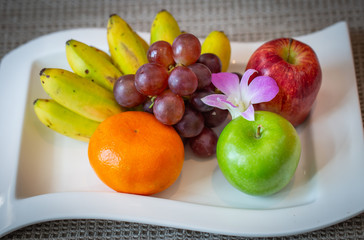 Assortment of fresh fruit on a white dish. Organic healthy fruit