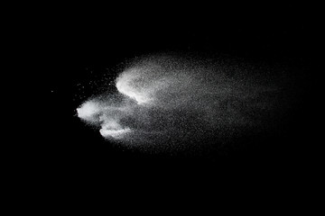 Freeze motion of white dust particles on black background. White powder explosion.