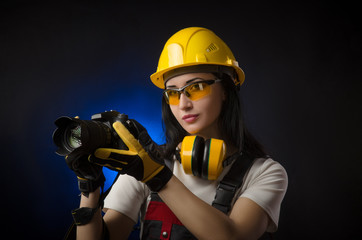 Fototapeta premium girl photographer at a construction site in a helmet with a DSLR camera