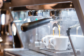 Close-up of espresso pouring from coffee machine in two white cups of coffee