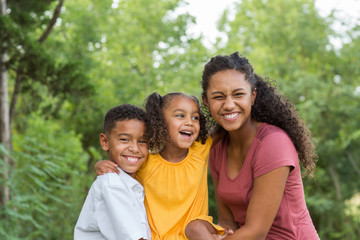 Brother and sisters playing and laughing in a field.