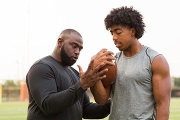 American Football coach training a young athlete.